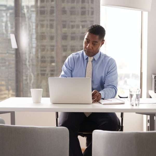 male-financial-advisor-in-modern-office-sitting-at-desk-working-on-laptop.jpg